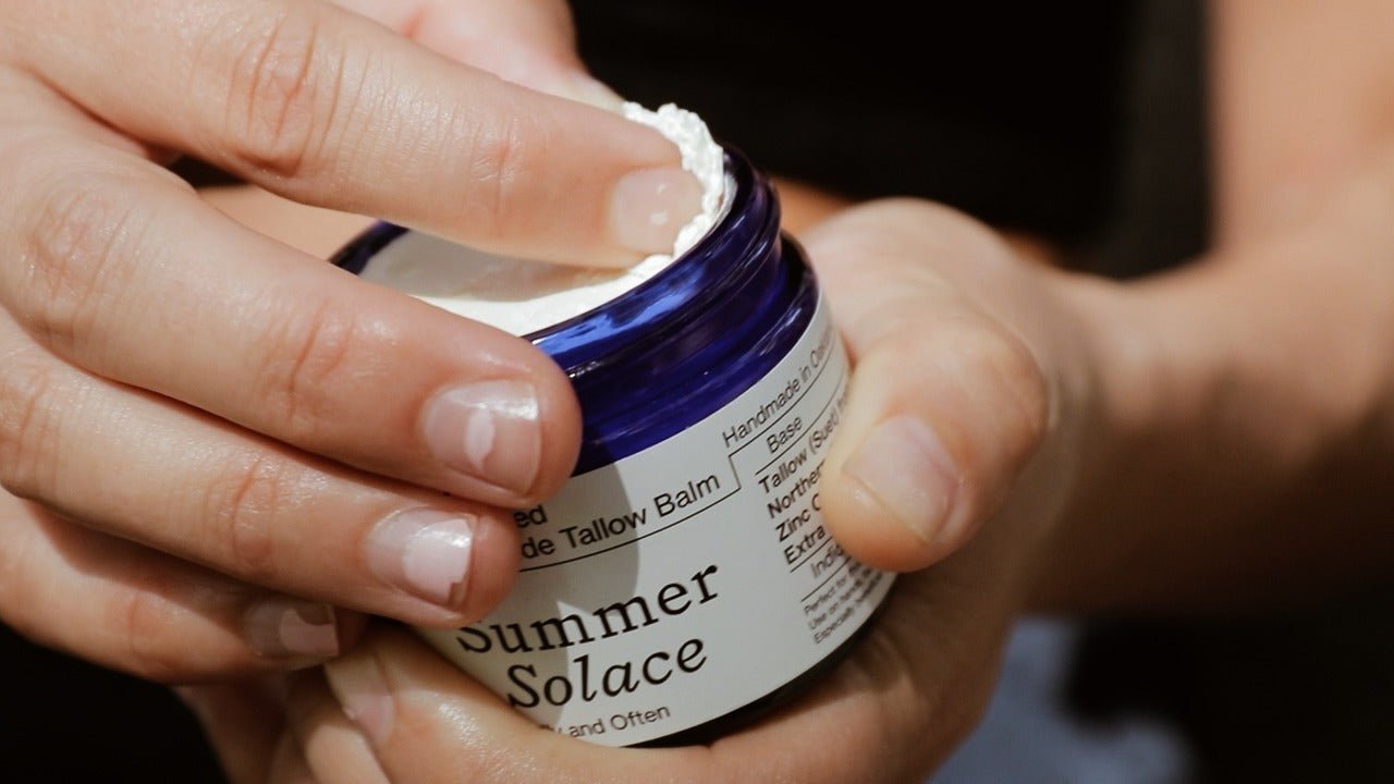 Close-up texture view of smooth, creamy, unwhipped suet tallow balm in a clear glass jar.